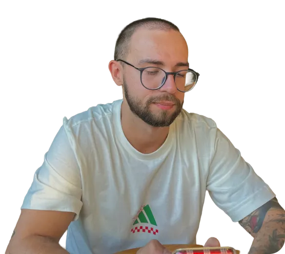 Guilherme Domingues, de óculos e camiseta clara, olhando para baixo.